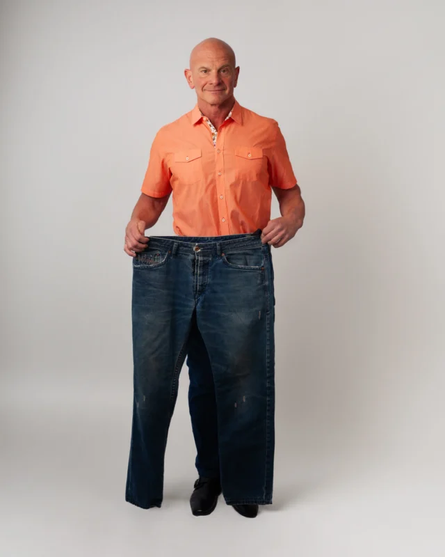 A man holding a pair of pants he used to wear prior to Options Medical.