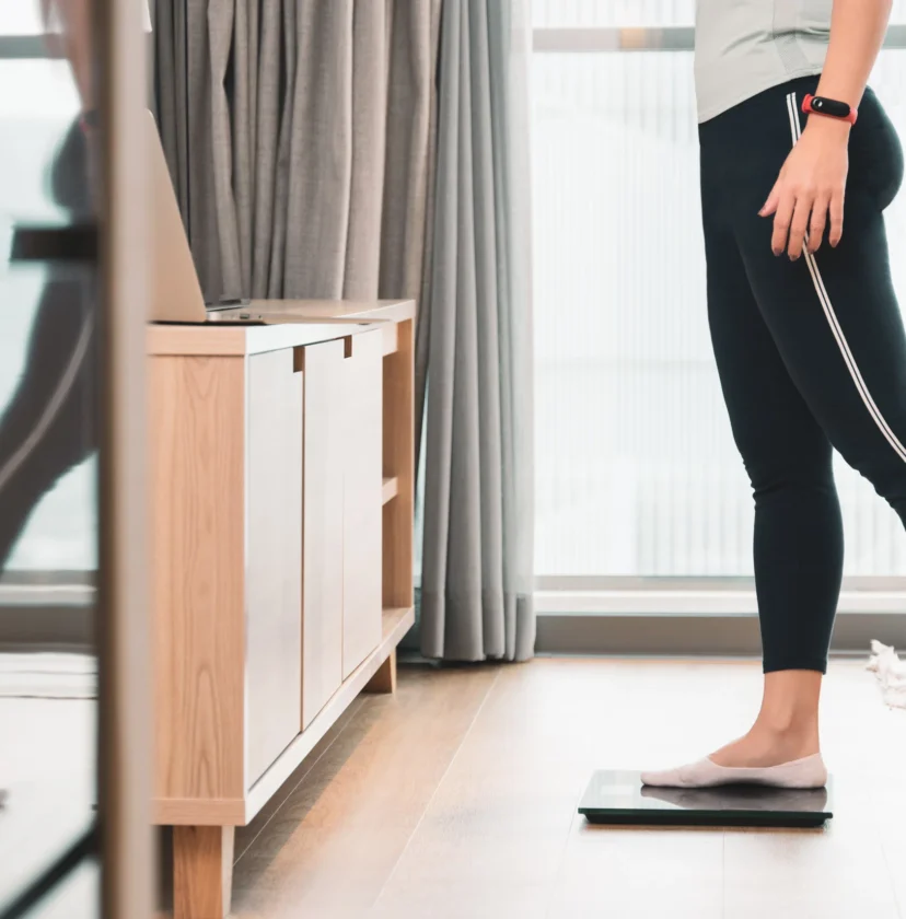 Person standing on a digital scale in a modern room with wooden flooring and furniture.