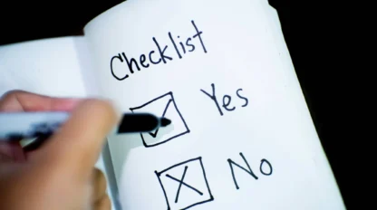A hand is marking a checklist on paper, placing a checkmark next to "Yes" and leaving the box next to "No" unchecked.