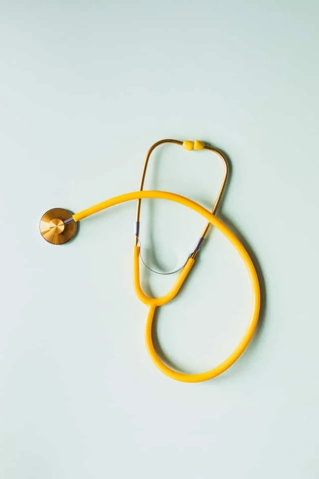 A yellow stethoscope is placed on a light blue surface.