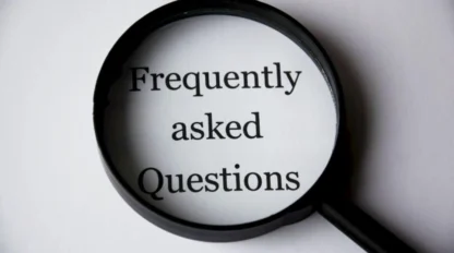 A magnifying glass focuses on the words "Frequently asked Questions" printed on white paper.