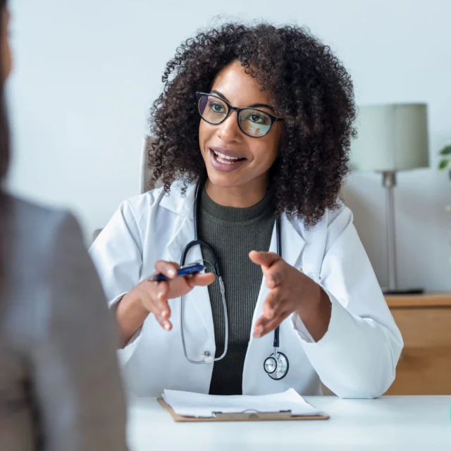 A doctor talking while explaining medical treatment to patient in the consultation.