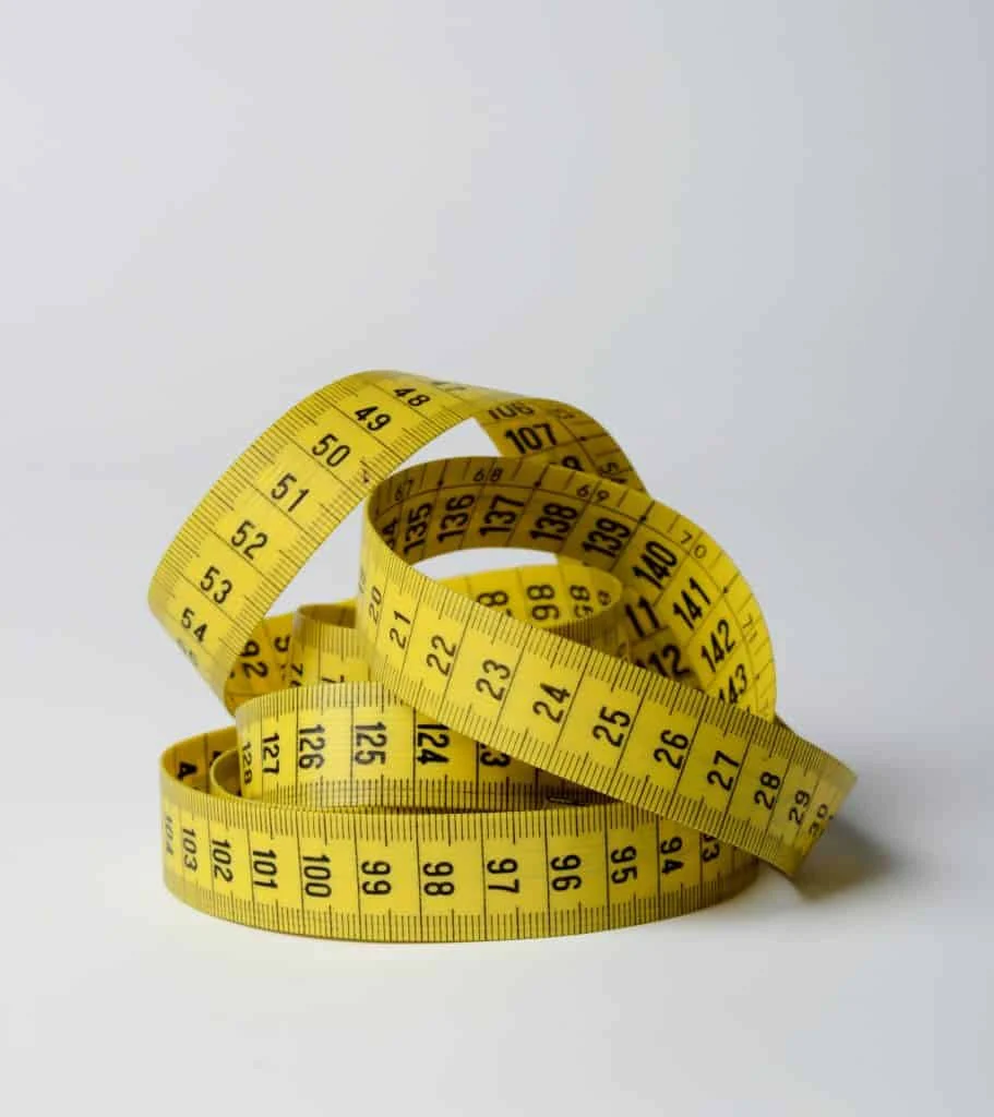 A yellow measuring tape with black numbers is coiled on a plain white surface.