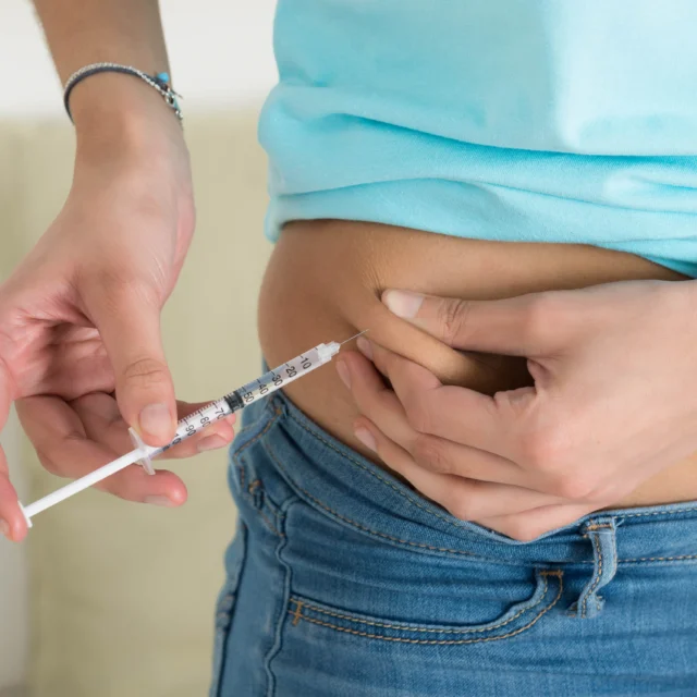 A patient using an injection on their abdomen.