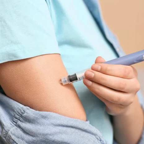 A patient giving themself an injection on their arm.