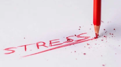 A red pencil underlines the word "STRESS" written on white paper, with pencil shavings scattered around.