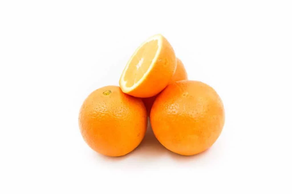 Four oranges are stacked on a white background, with one orange cut in half and placed on top, showing the inside.