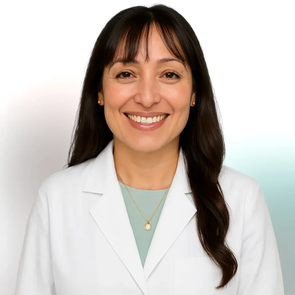 A woman in a white lab coat smiles at the camera against a plain background.