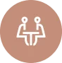 Icon depicting two people sitting at a table facing each other, shown in white on a circular brown background.