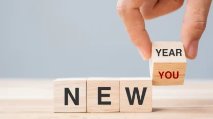 A hand placing a block on a stack of wood blocks.