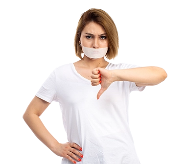 Woman with tape over her mouth, wearing a white shirt, giving a thumbs-down gesture with one hand while resting her other hand on her hip, expressing disapproval or being silenced.