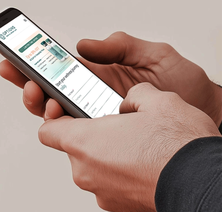 A person holds a smartphone in both hands, browsing a website about birth control options with information about different contraceptive methods. The site features images of products and a form for entering information.